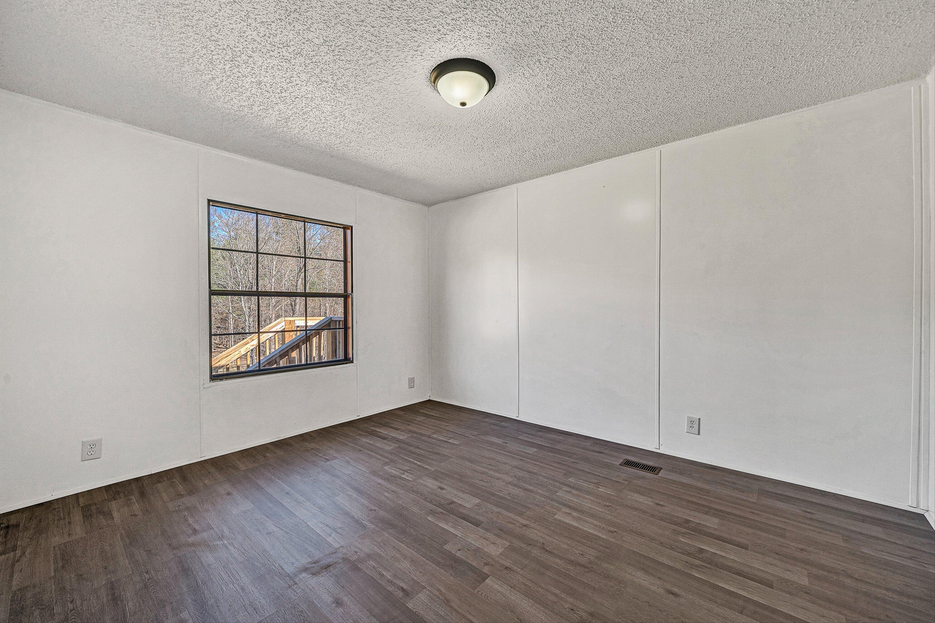 1155 Stonewall Road Blue Ridge, VA 24064 - Photo 20 of 43 an empty room with wooden floor and windows