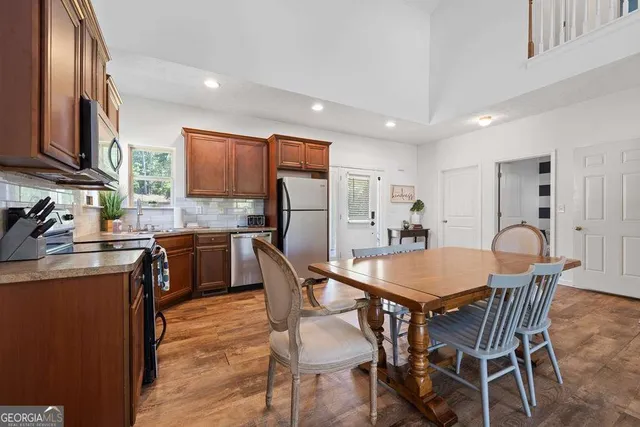 a kitchen with stainless steel appliances granite countertop a stove a refrigerator a kitchen island and chairs