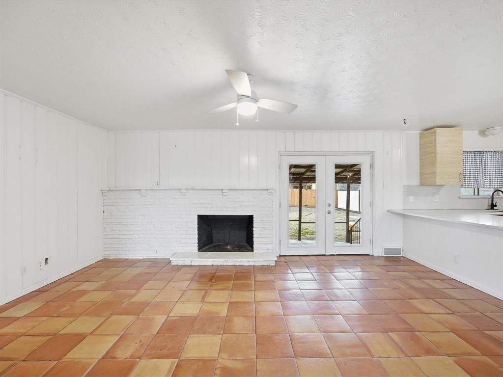 514 West Ridgewood Drive Garland, TX 75041 - Photo 7 of 39 a view of an empty room with a kitchen and a fireplace