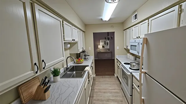 a kitchen with granite countertop a refrigerator a stove top oven a sink and dishwasher