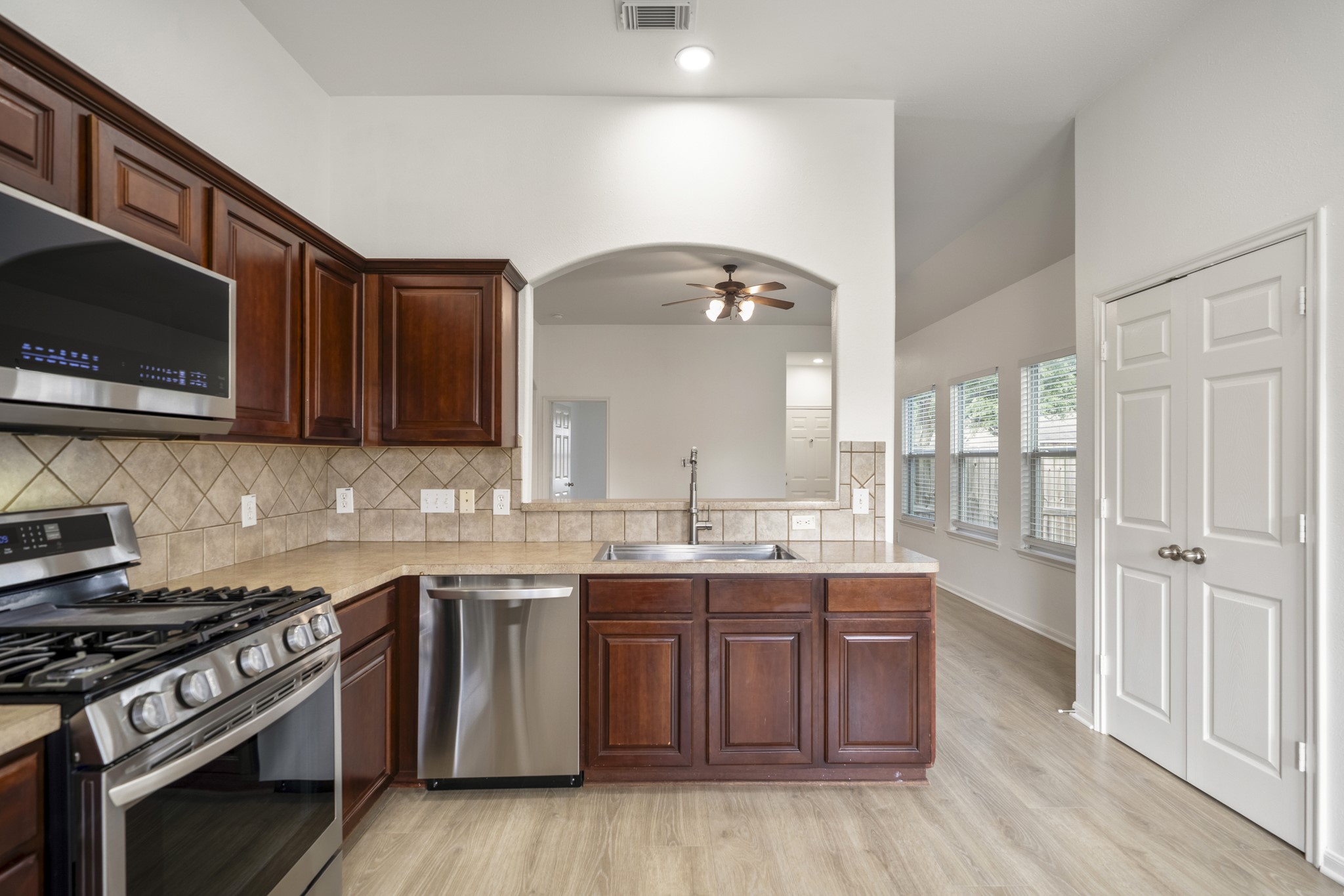 21810 Mansfield Bluff Lane Spring, TX 77379 - Photo 11 of 34 From this angle, the kitchen connects back toward the living area through the arched opening, keeping everything visually open while still defining each space. Stainless steel appliances line one side, while the pantry and additional storage sit just beyond, keeping everyday functionality within reach.