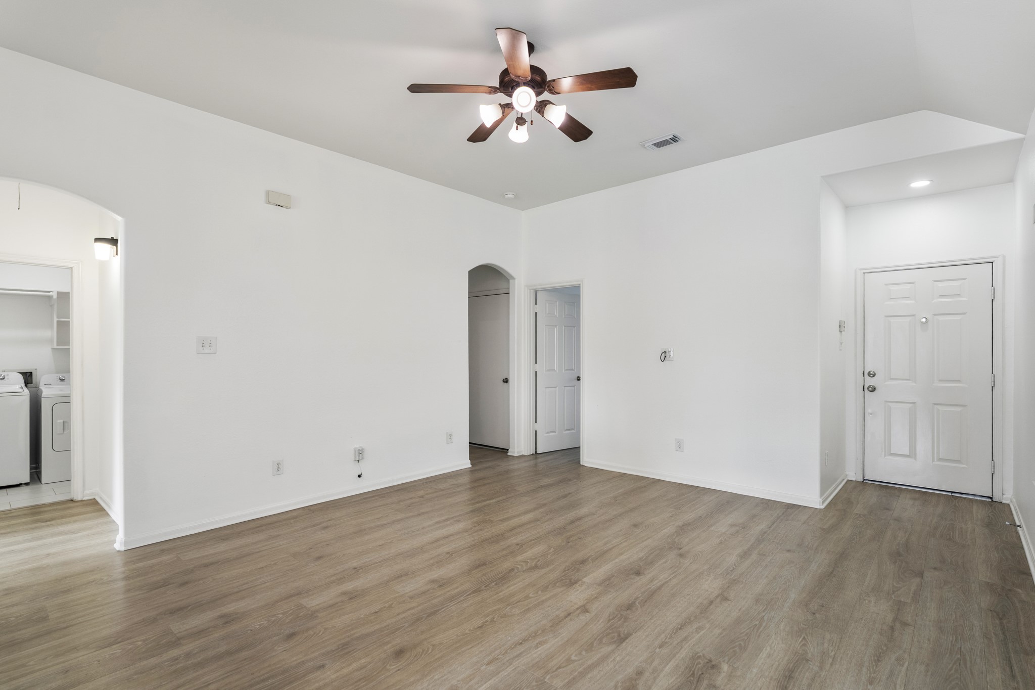 21810 Mansfield Bluff Lane Spring, TX 77379 - Photo 15 of 34 Coming out of the kitchen, this view looks back across the living area with the front door ahead to the right. Two openings to the left lead toward the hallway and one of the secondary bedrooms, while just out of view to the left is access to the laundry room and primary suite.