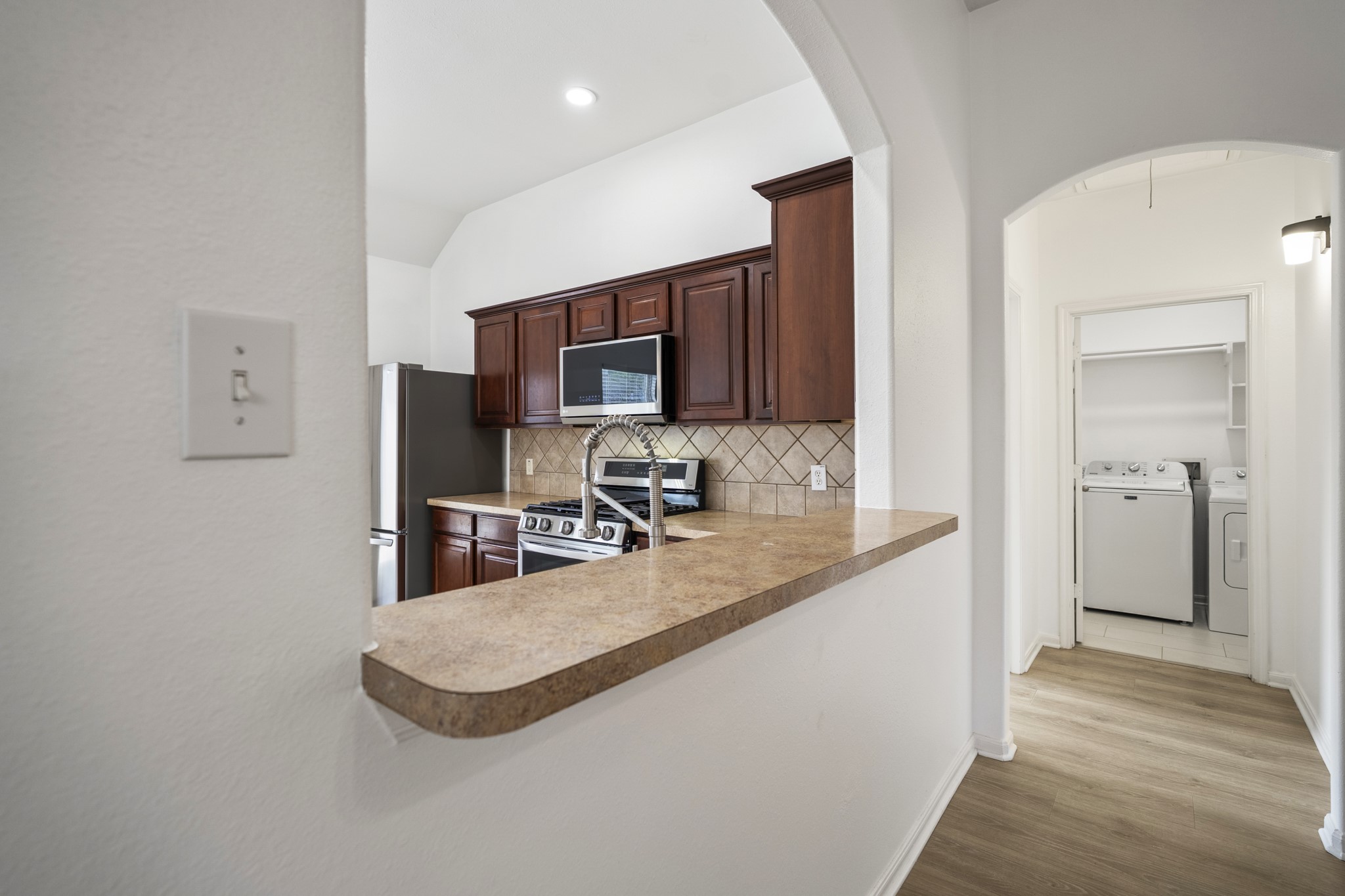 21810 Mansfield Bluff Lane Spring, TX 77379 - Photo 16 of 34 Turning left from the kitchen toward the primary suite, the breakfast bar comes into view, offering a spot for casual seating while still looking back into the kitchen. From here, the layout continues toward the primary bedroom and laundry room just ahead.