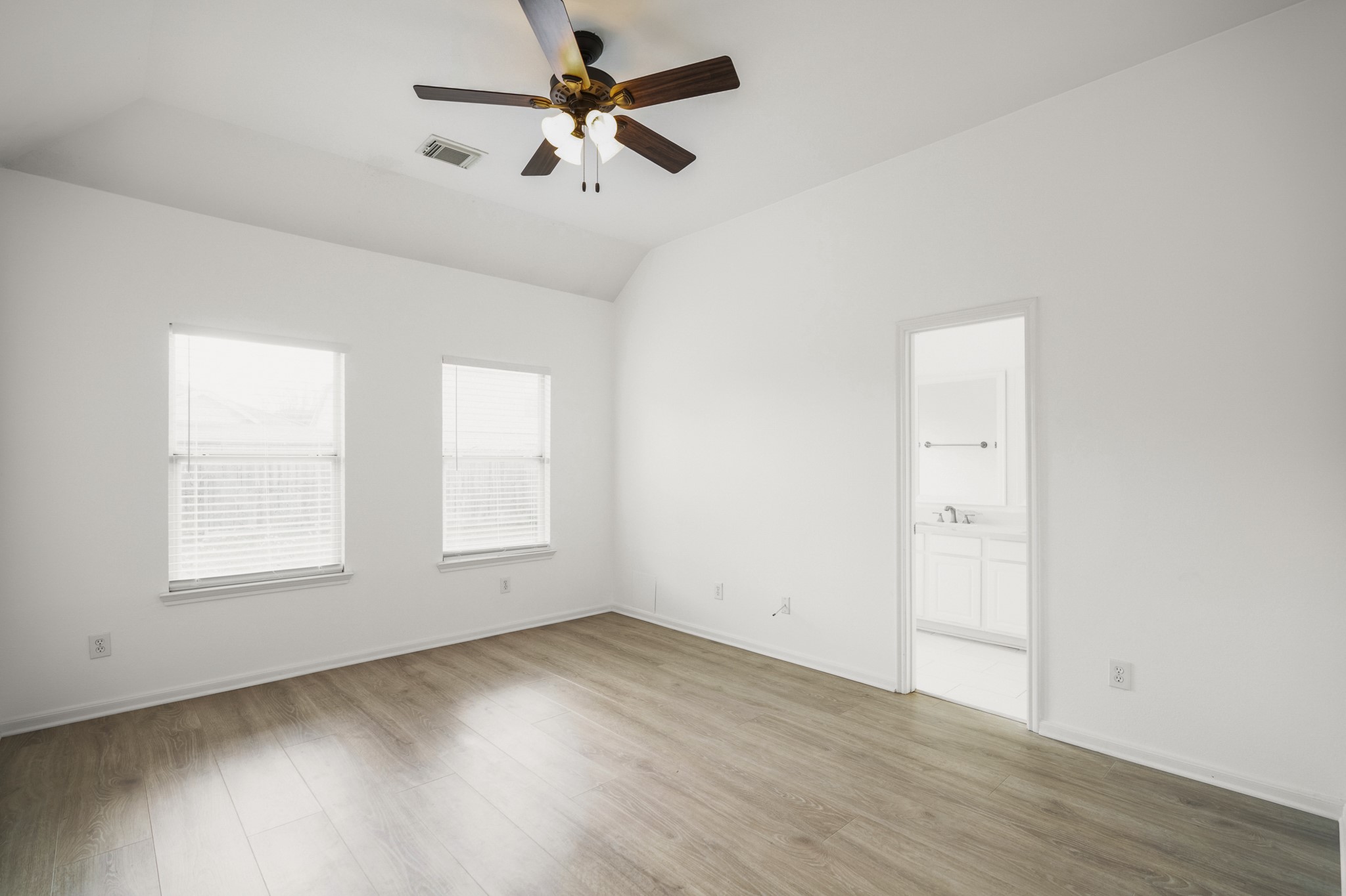 21810 Mansfield Bluff Lane Spring, TX 77379 - Photo 17 of 34 The primary suite offers a bright, comfortable space with natural light coming through the windows and a ceiling fan overhead. Straight ahead, the doorway leads into the remodeled bathroom.