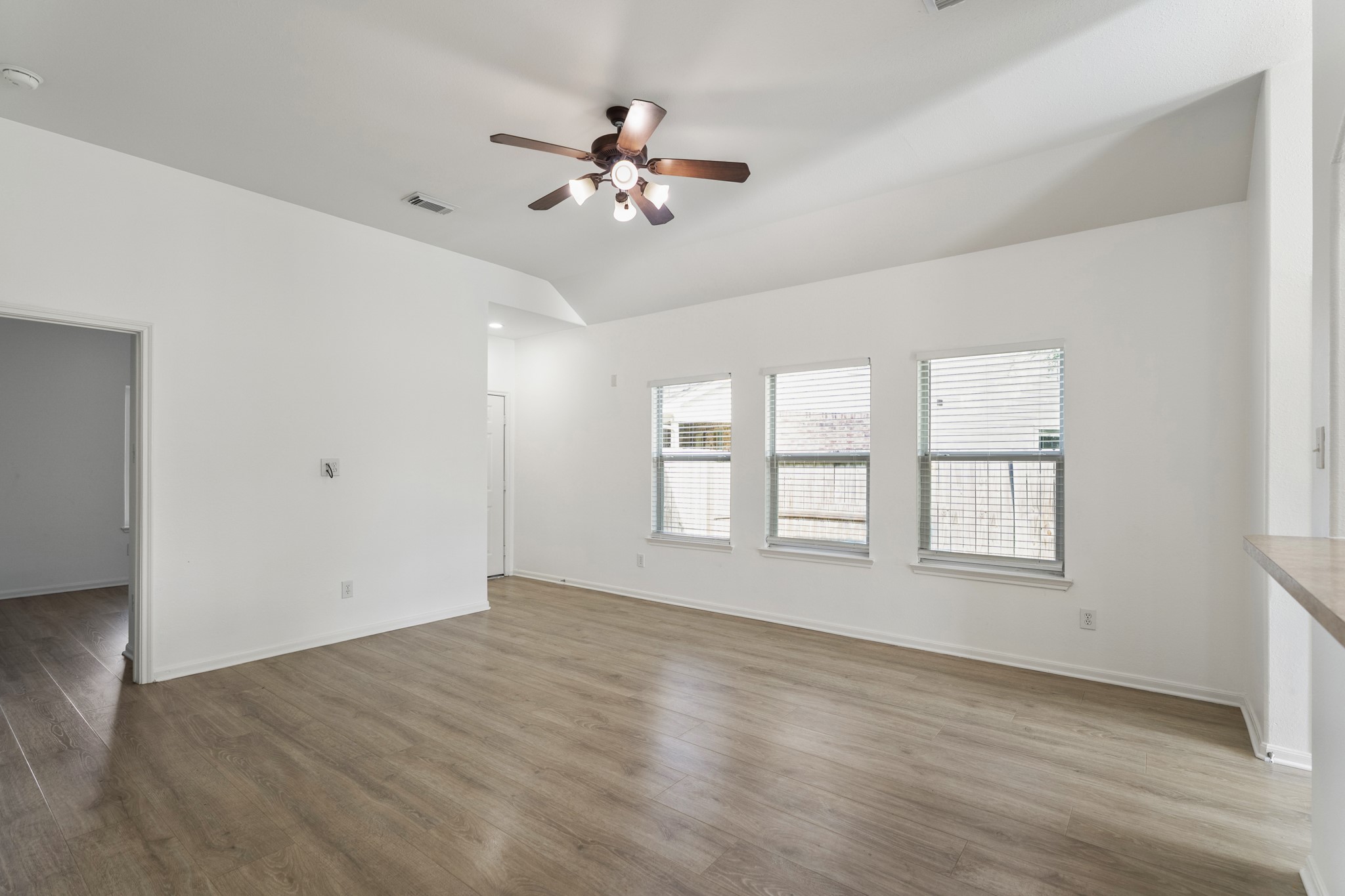 21810 Mansfield Bluff Lane Spring, TX 77379 - Photo 22 of 34 Coming back into the living area from the primary bedroom, the space opens up again with natural light from the windows. To the immediate left is one of the secondary bedrooms, while across the room is the front door. Off to the right, just out of view, the layout continues back into the kitchen and breakfast area.