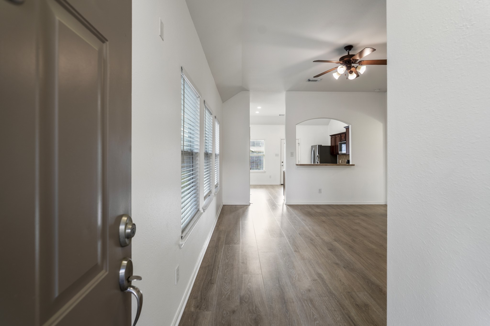 21810 Mansfield Bluff Lane Spring, TX 77379 - Photo 4 of 34 Step inside to find vinyl plank flooring running throughout—no carpet anywhere—setting a clean, low-maintenance tone from the start. Just ahead, the living area opens up, and beyond we get a peek into the kitchen beyond.