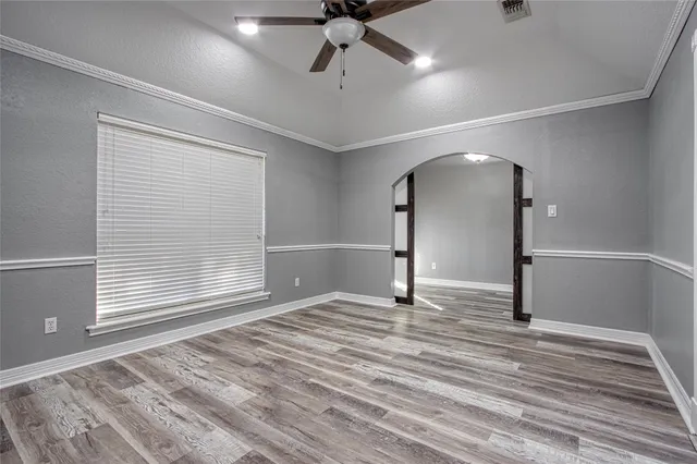 a view of empty room with wooden floor and fan