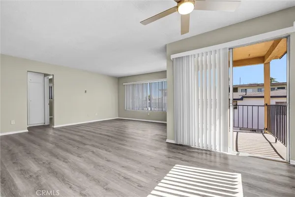 an empty room with wooden floor closet and windows