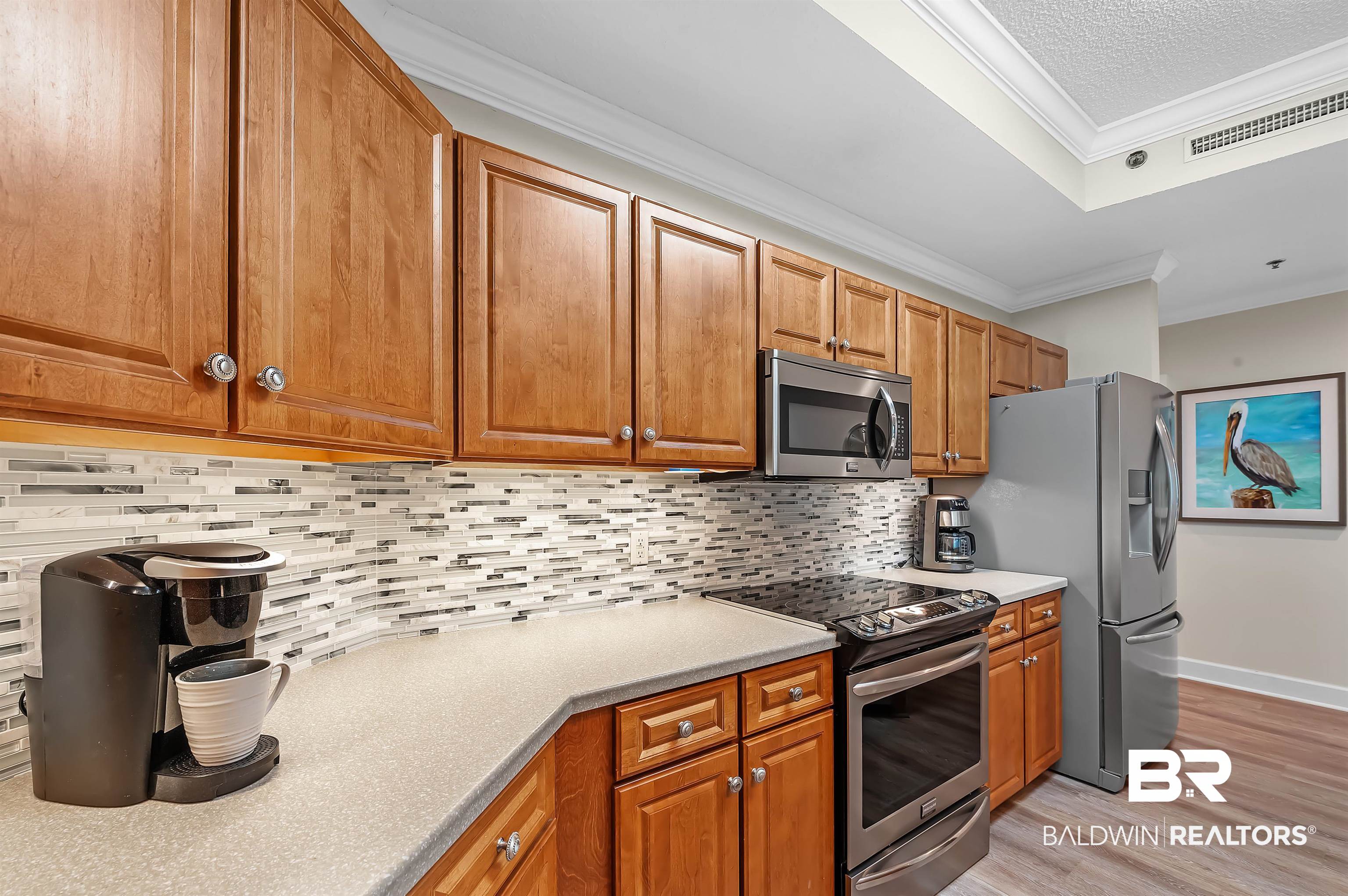 27582 Canal Road, Unit 2104 Orange Beach, AL 36561 - Photo 13 of 35 Kitchen with ornamental molding, backsplash, appliances with stainless steel finishes, and light wood-type flooring