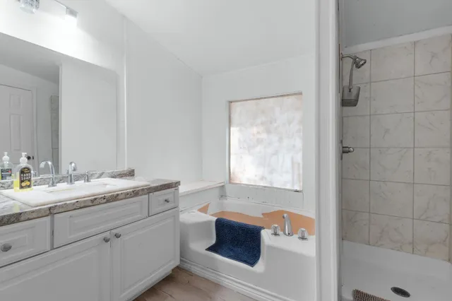 a bathroom with a granite countertop sink mirror and bathtub
