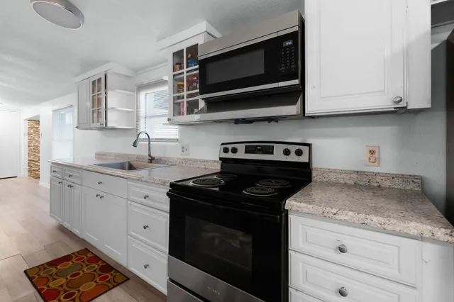 a kitchen with stainless steel appliances granite countertop white cabinets granite counter tops and a wooden floors