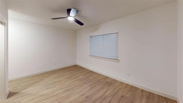 an empty room with wooden floor chandelier fan and windows