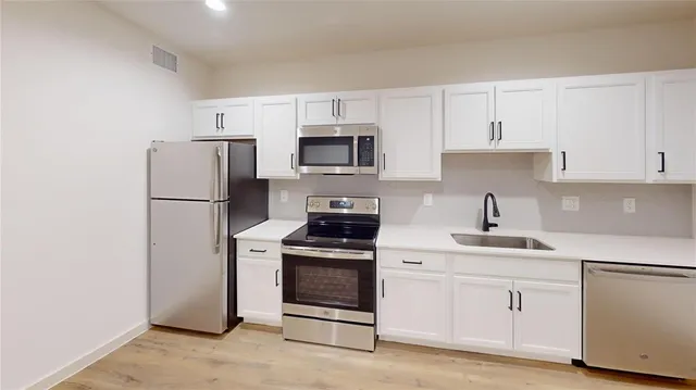 a kitchen with white cabinets and stainless steel appliances