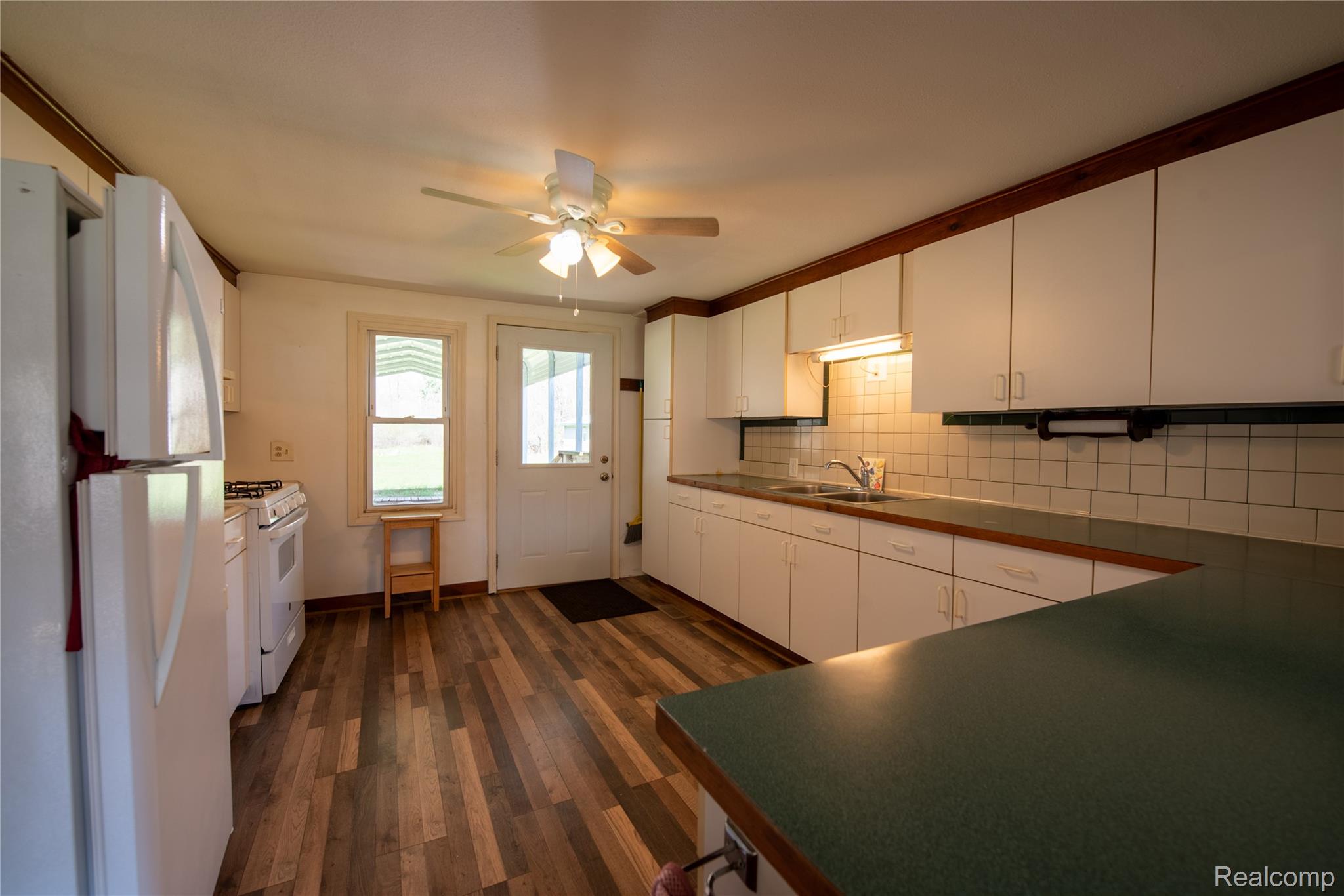1190 Meadow Road Tawas City, MI 48763 - Photo 24 of 26 Kitchen with white appliances, dark wood finished floors, dark countertops, and white cabinetry