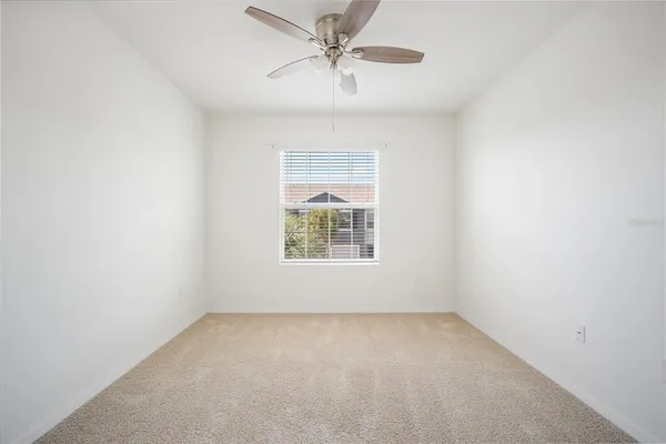 an empty room with a window and a fan
