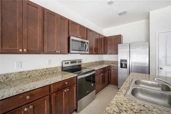 a kitchen with stainless steel appliances granite countertop a sink stove microwave and refrigerator
