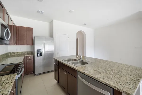 a kitchen with stainless steel appliances granite countertop a sink refrigerator and microwave