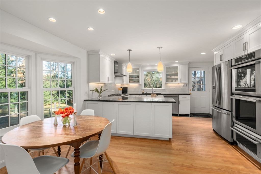 15 Bradyll Road Weston, MA 02493 - Photo 3 of 36 a kitchen with stainless steel appliances granite countertop a stove a sink a microwave a dining table and chairs