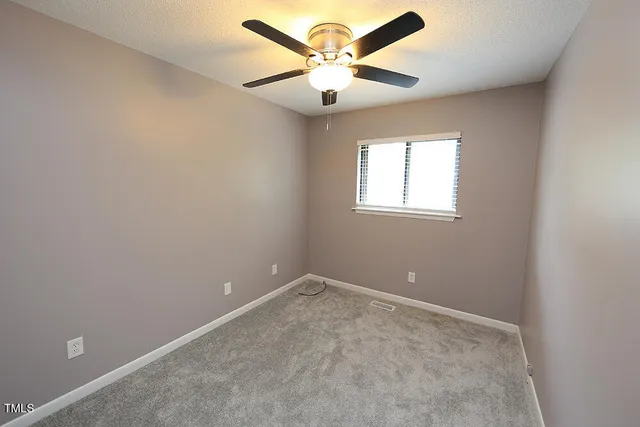 an empty room with a window and a fan