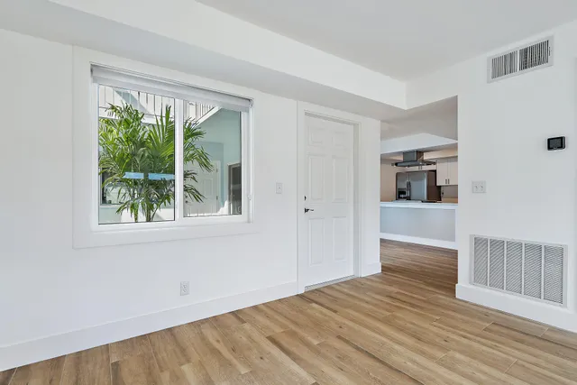 a view of empty room with wooden floor and fan