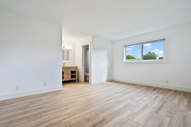 a view of empty room with wooden floor and window