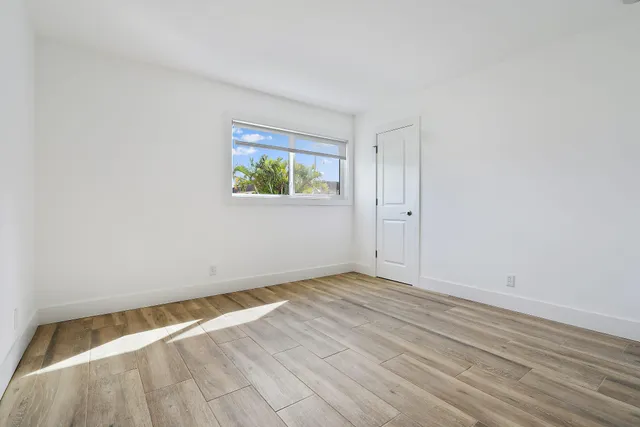 a view of an empty room with wooden floor and window