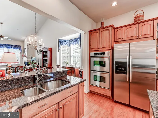 a kitchen with stainless steel appliances kitchen island granite countertop a stove a sink dishwasher a dining table and chairs with wooden floor