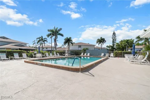 a view of a swimming pool with a lounge chair and palm trees