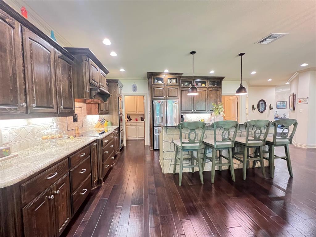 187 Private Road 5987 Yantis, TX 75497 - Photo 22 of 40 Kitchen with a kitchen breakfast bar, dark wood-type flooring, light stone countertops, a kitchen island, and tasteful backsplash