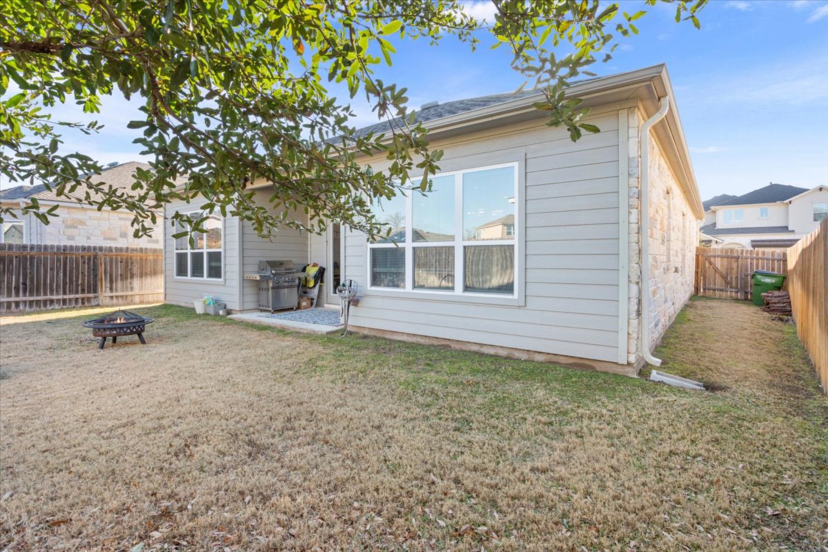 3814 Chance Loop Round Rock, TX 78628 - Photo 15 of 16 Back of property with a patio, an outdoor fire pit, a fenced backyard, and stone siding