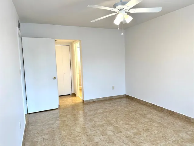an empty room with a ceiling fan and a window