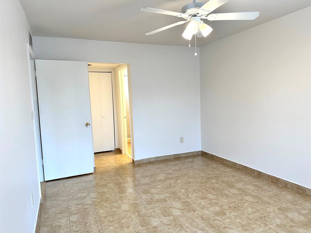 7355 West 4th Avenue, Unit 215 Hialeah, FL 33014 - Photo 8 of 17 an empty room with a ceiling fan and a window