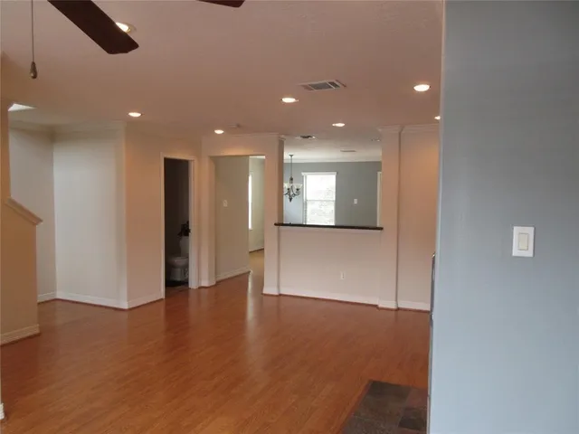 a view of an empty room with wooden floor and windows