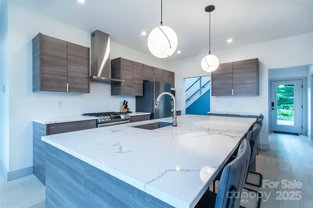 a kitchen with a stove a kitchen island a sink dishwasher a dining table and chairs with wooden floor