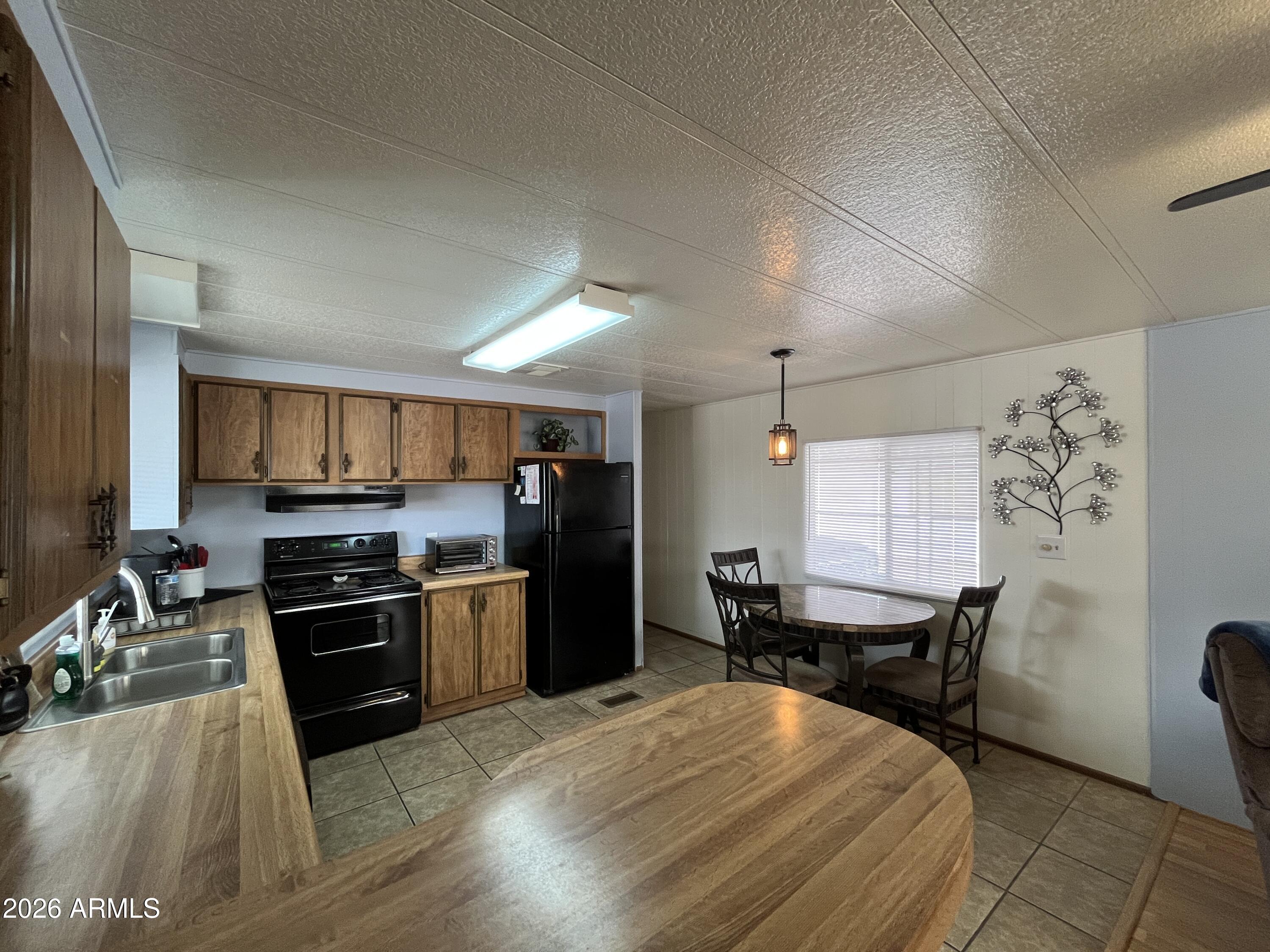 9302 East Broadway Road, Unit 179 Mesa, AZ 85208 - Photo 13 of 54 a kitchen with granite countertop a stove top oven a sink dishwasher a dining table and chairs with wooden floor