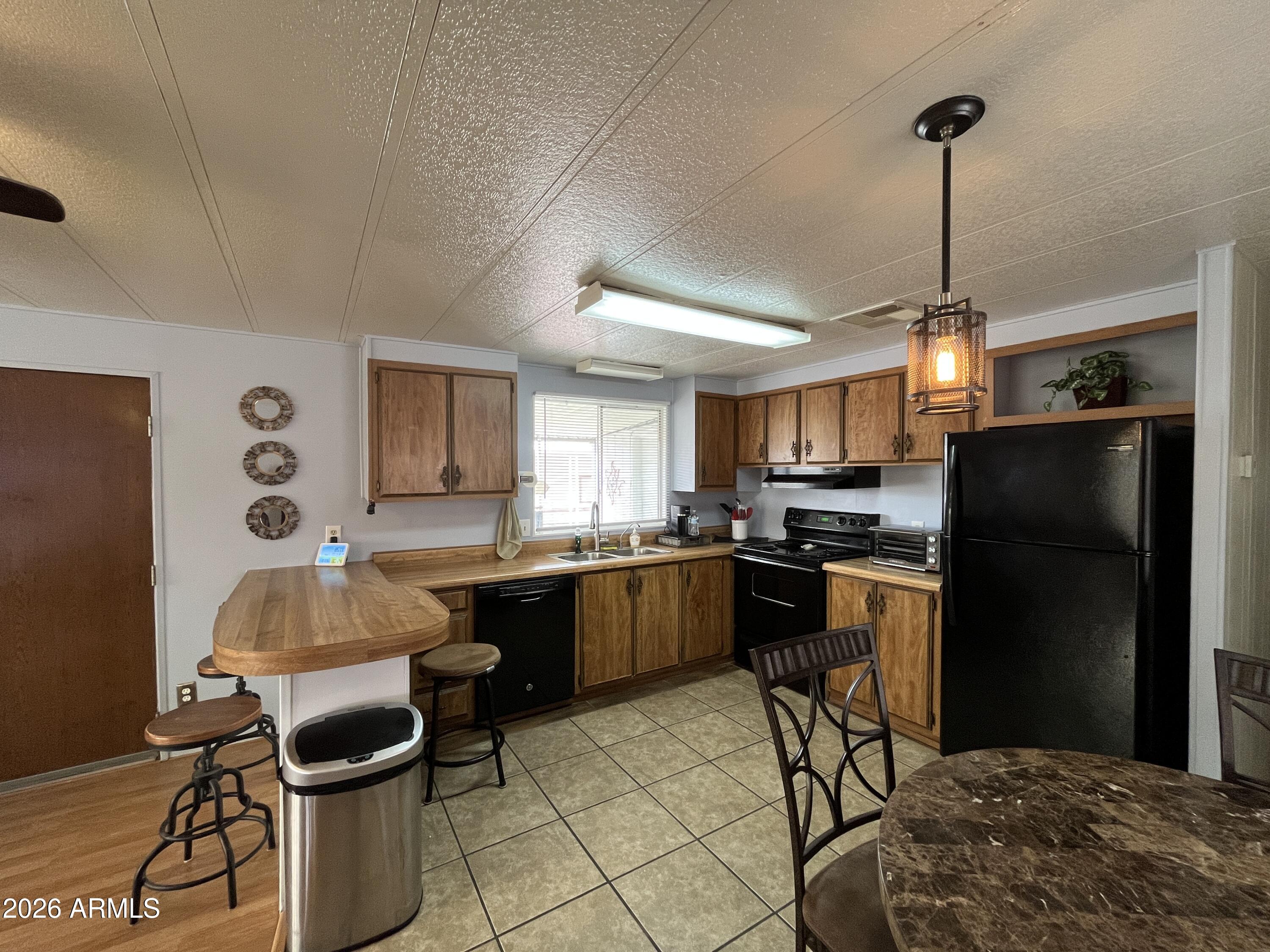 9302 East Broadway Road, Unit 179 Mesa, AZ 85208 - Photo 14 of 54 a kitchen with a refrigerator a stove a dining table and chairs with wooden floor