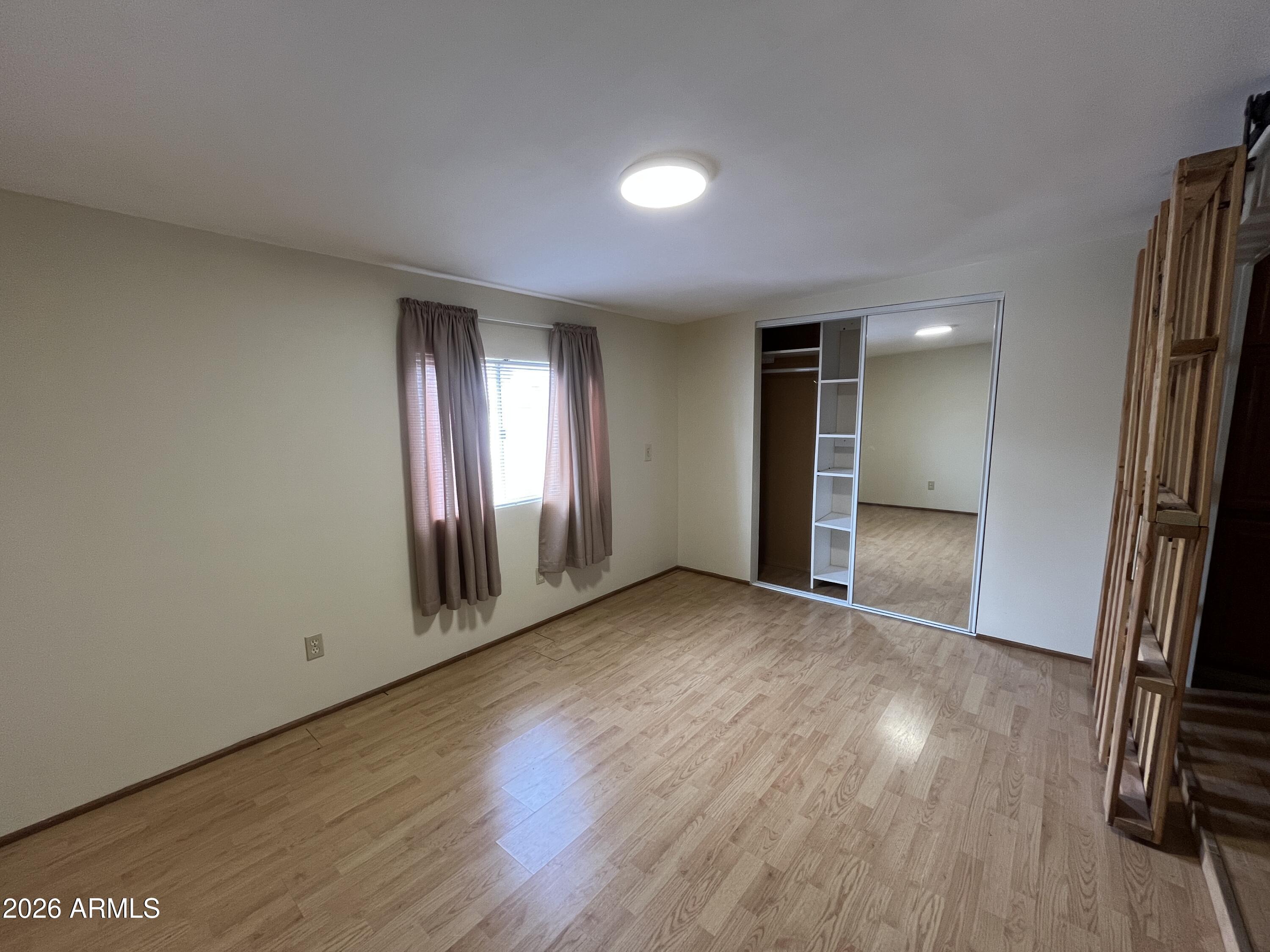 9302 East Broadway Road, Unit 179 Mesa, AZ 85208 - Photo 32 of 54 an empty room with wooden floor and a window