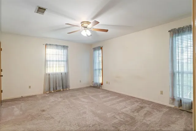 an empty room with windows and fan