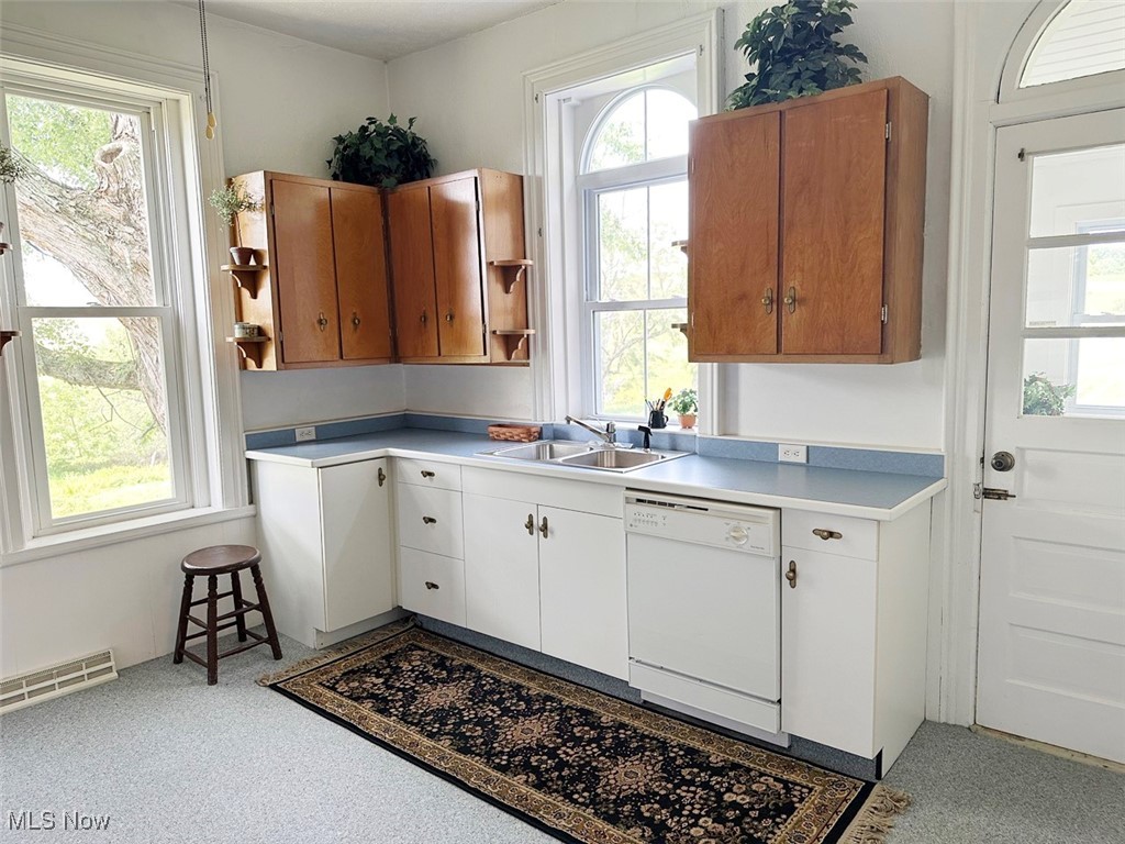 1241 Apollo Road Southeast Carrollton, OH 44615 - Photo 23 of 33 Kitchen with white cabinetry, sink, white dishwasher, and light colored carpet