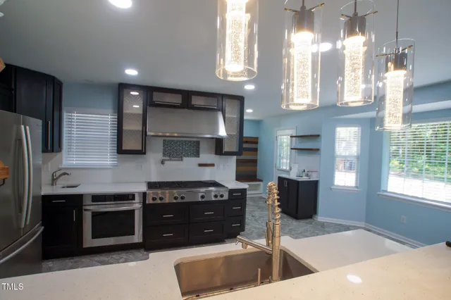 a kitchen with stainless steel appliances granite countertop a stove a sink and a refrigerator