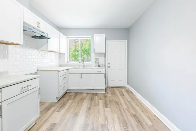 a view of a kitchen with white cabinets appliances and a window