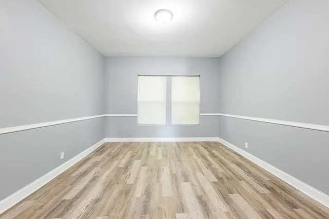 a view of an empty room with a window and wooden floor