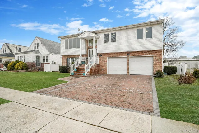 a view of a white house with a yard and large tree