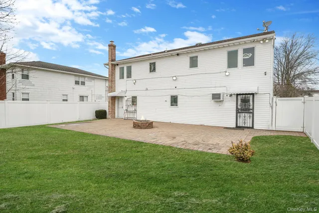 a view of a white house next to a yard with big trees