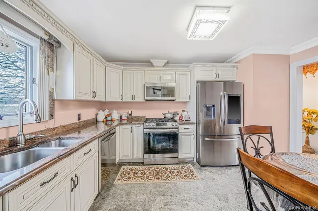 a kitchen with granite countertop white cabinets stainless steel appliances and a sink