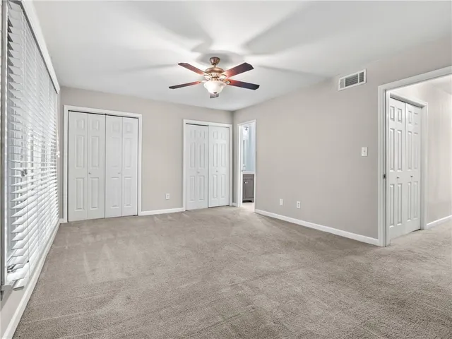 an empty room with windows and fan