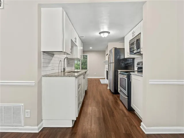a kitchen with stainless steel appliances a refrigerator and a wooden floor