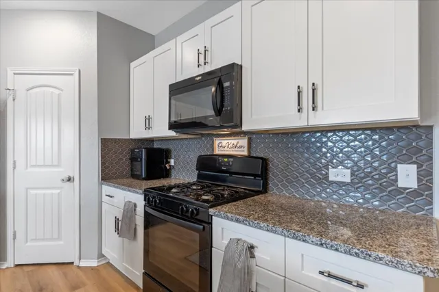 a kitchen with granite countertop white cabinets stainless steel appliances and a sink