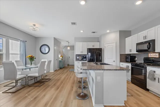 a large kitchen with stainless steel appliances granite countertop a stove a sink dishwasher a dining table and chairs with wooden floor