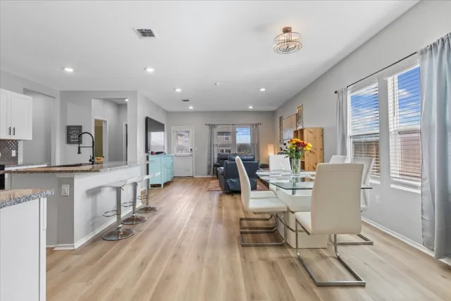a living room with furniture a dining table wooden floor and a large window